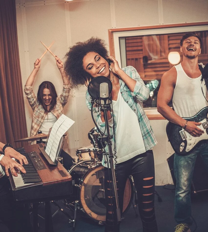 Student musicians playing and singing together in a practice room