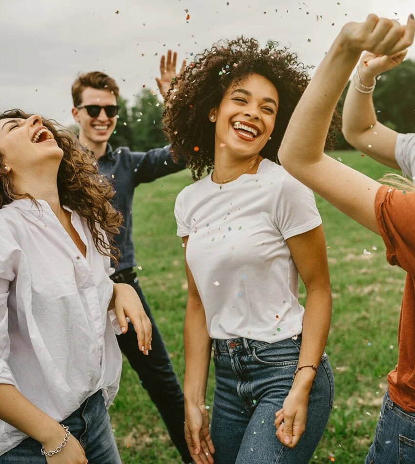 Young friends laughing and dancing together on a lawn