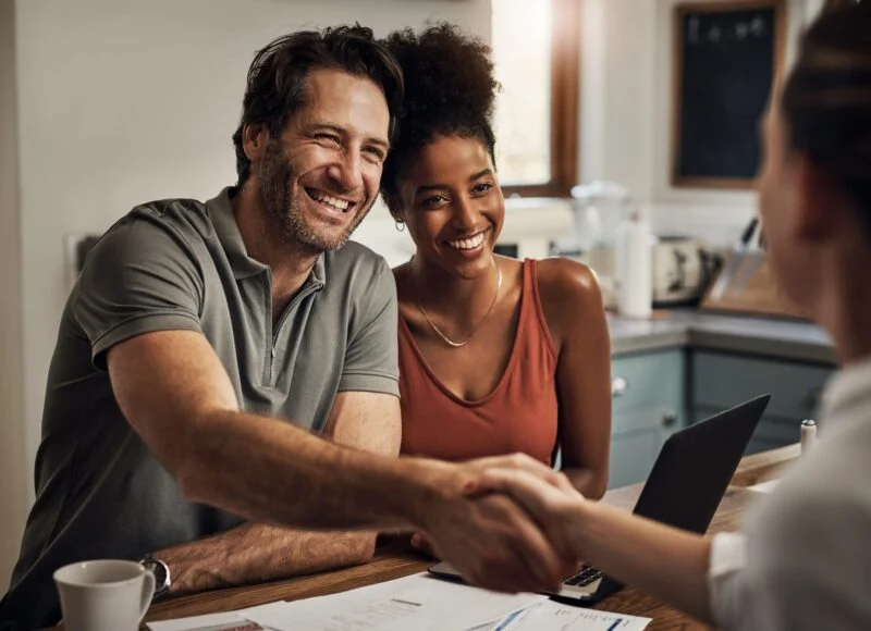 Smiling friends shaking hands across a table