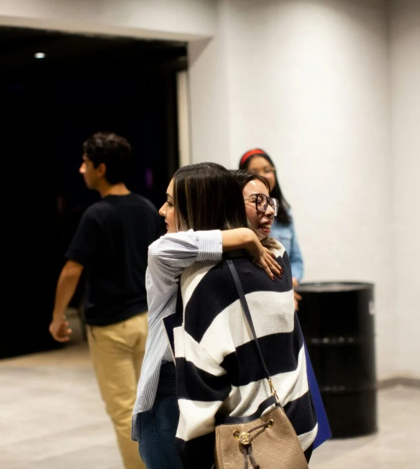 Two friends sharing a welcome hug in the church lobby